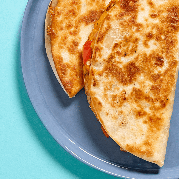 A close-up of two chicken quesadillas folded into  GMO-free flour crispy tortillas and griddled on the flat top until crispy
