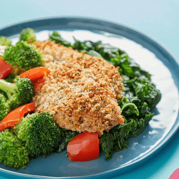 nutritious Parmesan Crusted Chicken on a bed of steamed kale, broccoli and peppers making this dish low-carb and high-protein