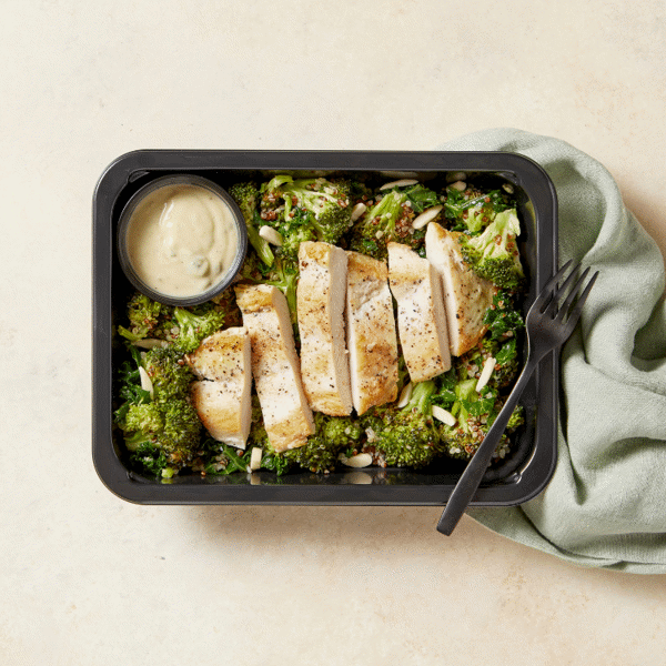 Freshly prepared Chicken Caesar, completed with tri-color quinoa and fiber-rich broccoli with a side of dressing in a BPA-free container