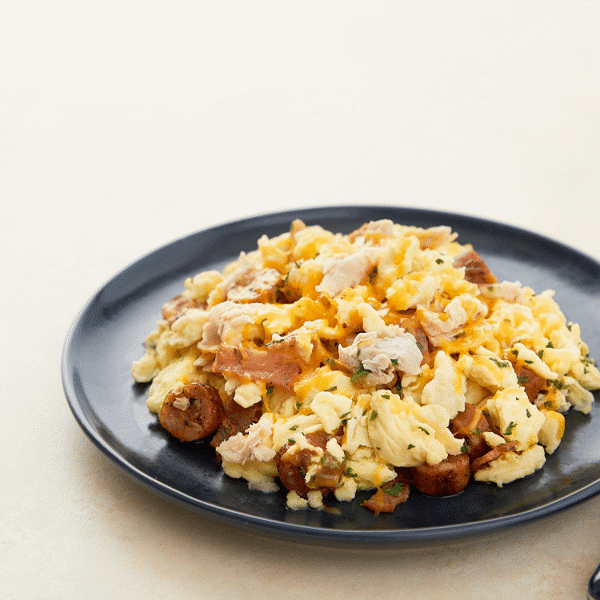 Ready-to-eat high-protein, gluten-free & low-carb meal prep made of scrambled eggs, chicken bacon, sausage, caramelized onions & cheddar.