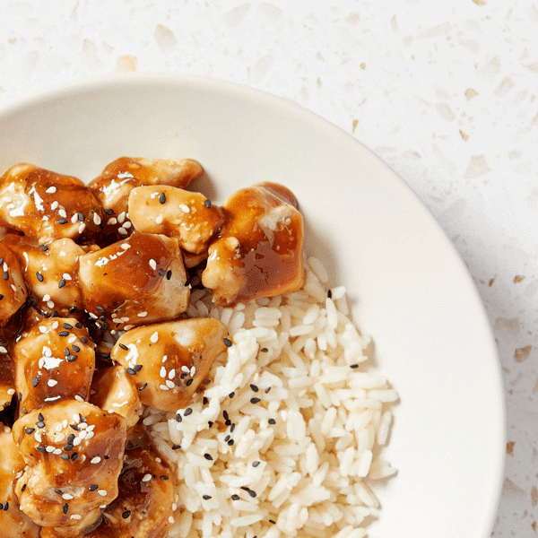 A close-up of Fitlife Foods' healthy dairy-free Bourbon Street marinated chicken served with rice and topped with sesame seeds