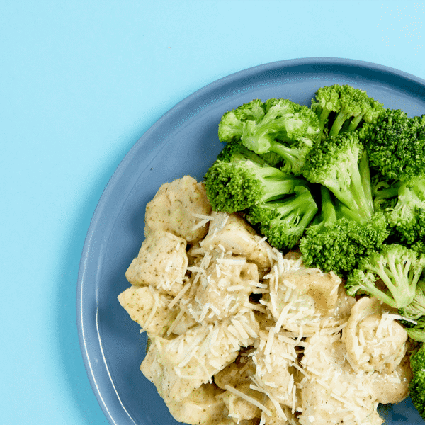Healthy meal that is made whole wheat cheese tortellini, roasted chicken, pesto-alfredo sauce, served with a side of nutrient-rich broccoli.