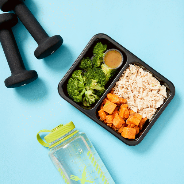 Grilled chicken, roasted sweet potatoes, and steamed broccoli accompanied with citrus sauce all packaged in a food-safe container