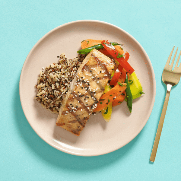 A healthy meal with grilled salmon, brushed with miso, accompanied by veggies and brown rice quinoa – a nutritious dinner.