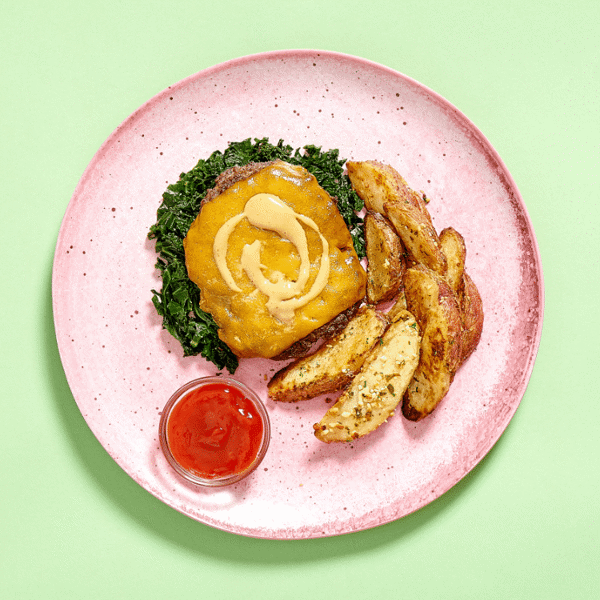 Gluten-free, low-carb dinner with Fitlife Foods' Grill House Burger topped with kale, cheddar, and secret sauce with a side of potato wedges.