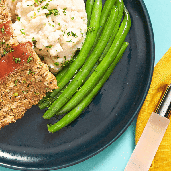 A close-up of gluten-free and low-carb Turkey meatloaf, freshly made and paired with sides of cauliflower mash and green beans