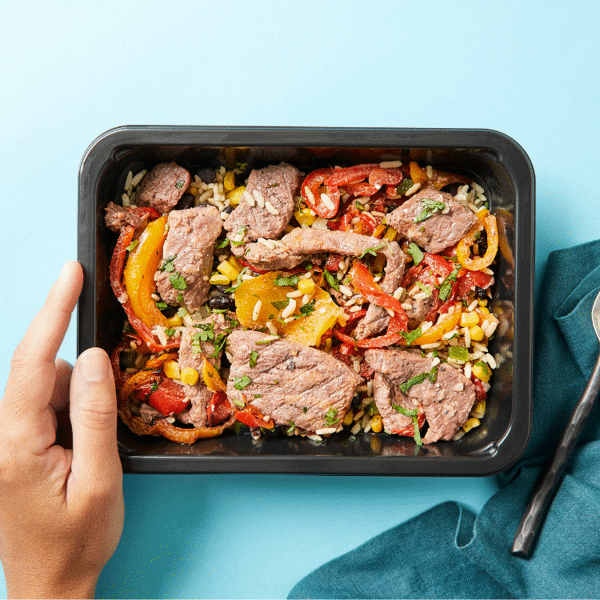 Steak Fajita Bowl is made of marinated steak, roasted bell peppers, and black beans over cilantro lime rice and served in a food-safe box