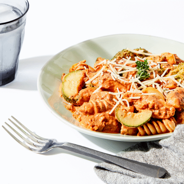 The Cajun Chicken Pasta on a plate with napkin, fork and glass of water.