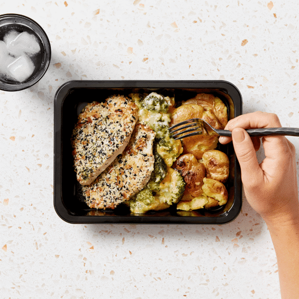 Chicken breast is served with roasted baby potatoes and cheesy broccoli au gratin, all packaged in a microwavable container.