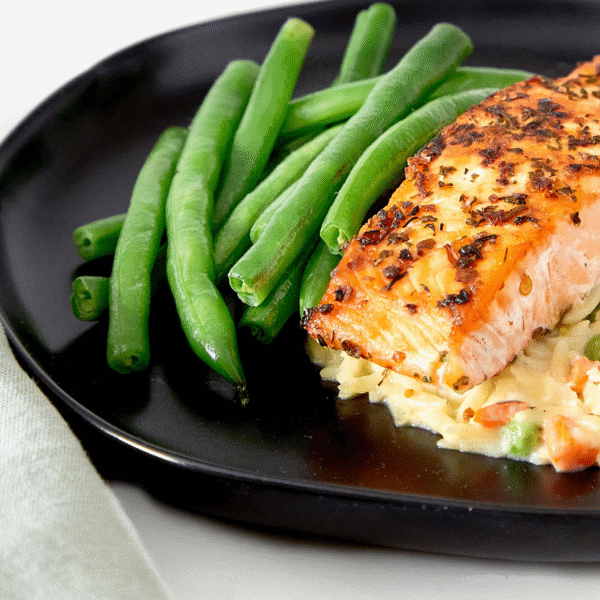 A close-up of pan seared Atlantic salmon on top of thinly laid pasta dish made with Greek yogurt and seasoned green beans