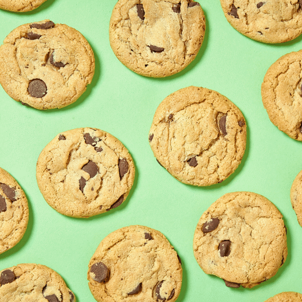 Bunch of dairy-Free Chocolate Chip Cookies with a golden-brown exterior with melty, gooey chocolate chips on a green background