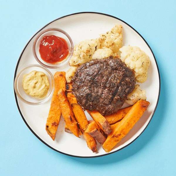 Nutritious meal with a bison burger featuring crimini mushrooms paired with freshly roasted cauliflower and sweet potato fries.