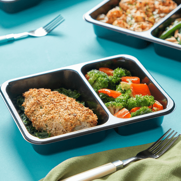 Low Carb Parmesan Crusted Chicken accompanied by steamed kale, broccoli, and peppers in a microwave-safe container for lunch